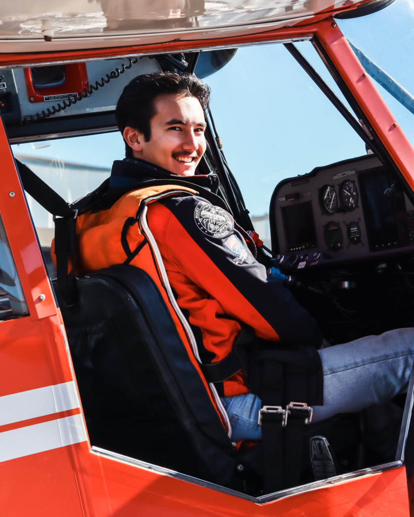 Man in orange jacket smiling in an orange plane